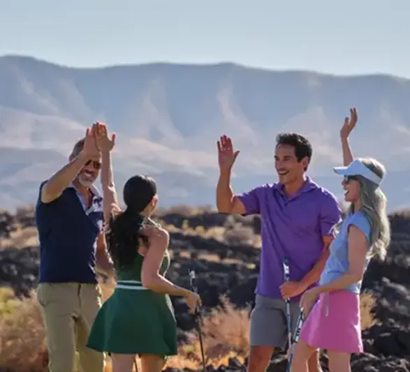 Group of people celebrating together on a golf course with desert mountains in the background.